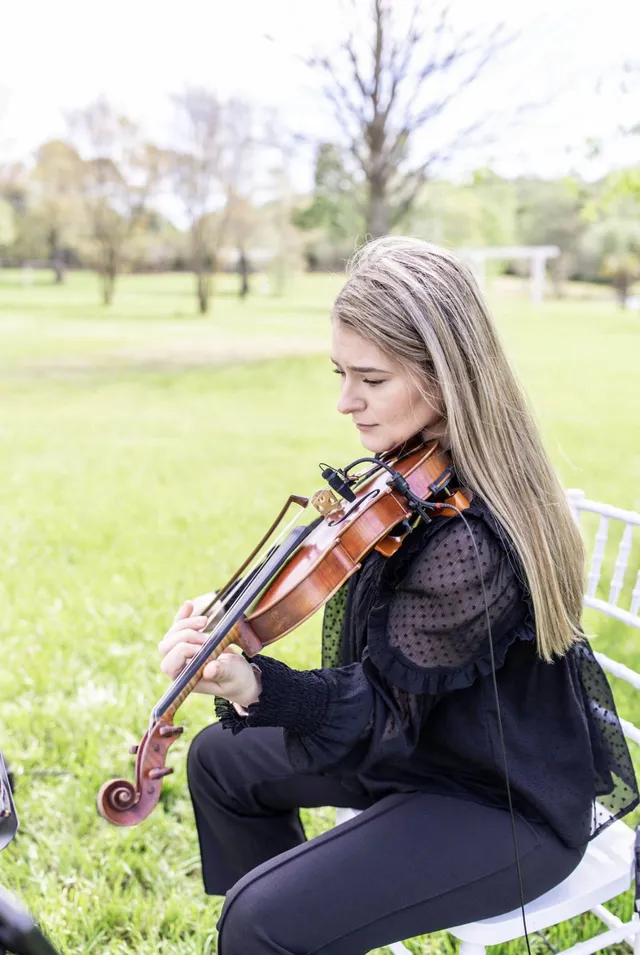 Solo violinist performing on a lawn at an outdoor wedding ceremony