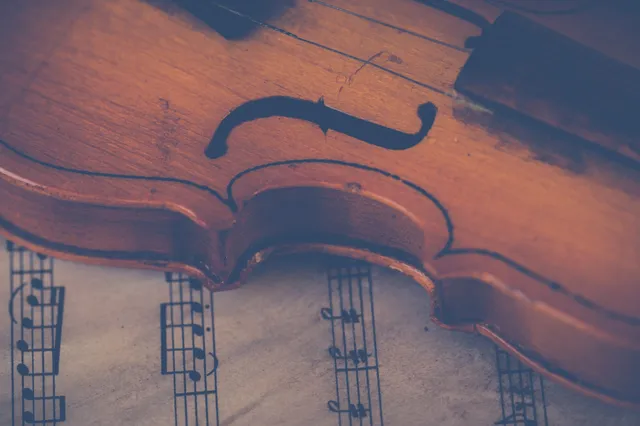 Violin resting on sheet music in warm moody editorial light