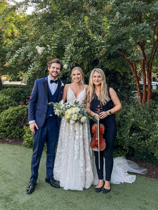 Violinist with couple in garden setting with lush green backdrop