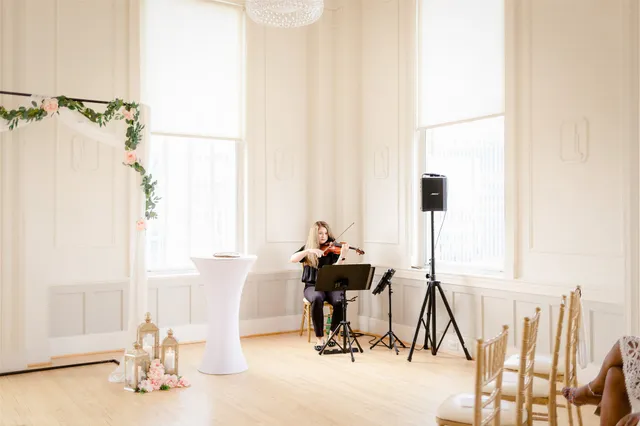 White classical ballroom with crystal chandelier and floral garland arch, wedding ceremony