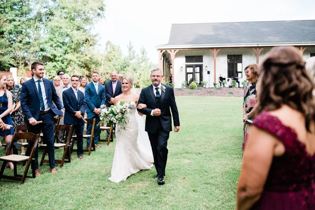 Wedding ceremony processional at elegant white farm venue with violinist in background