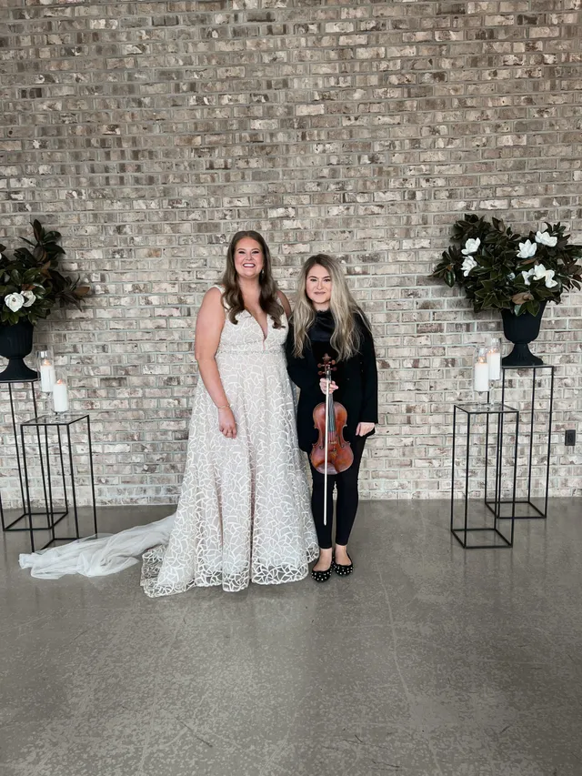Artist and bride at industrial brick venue with candle pedestals and magnolia arrangements