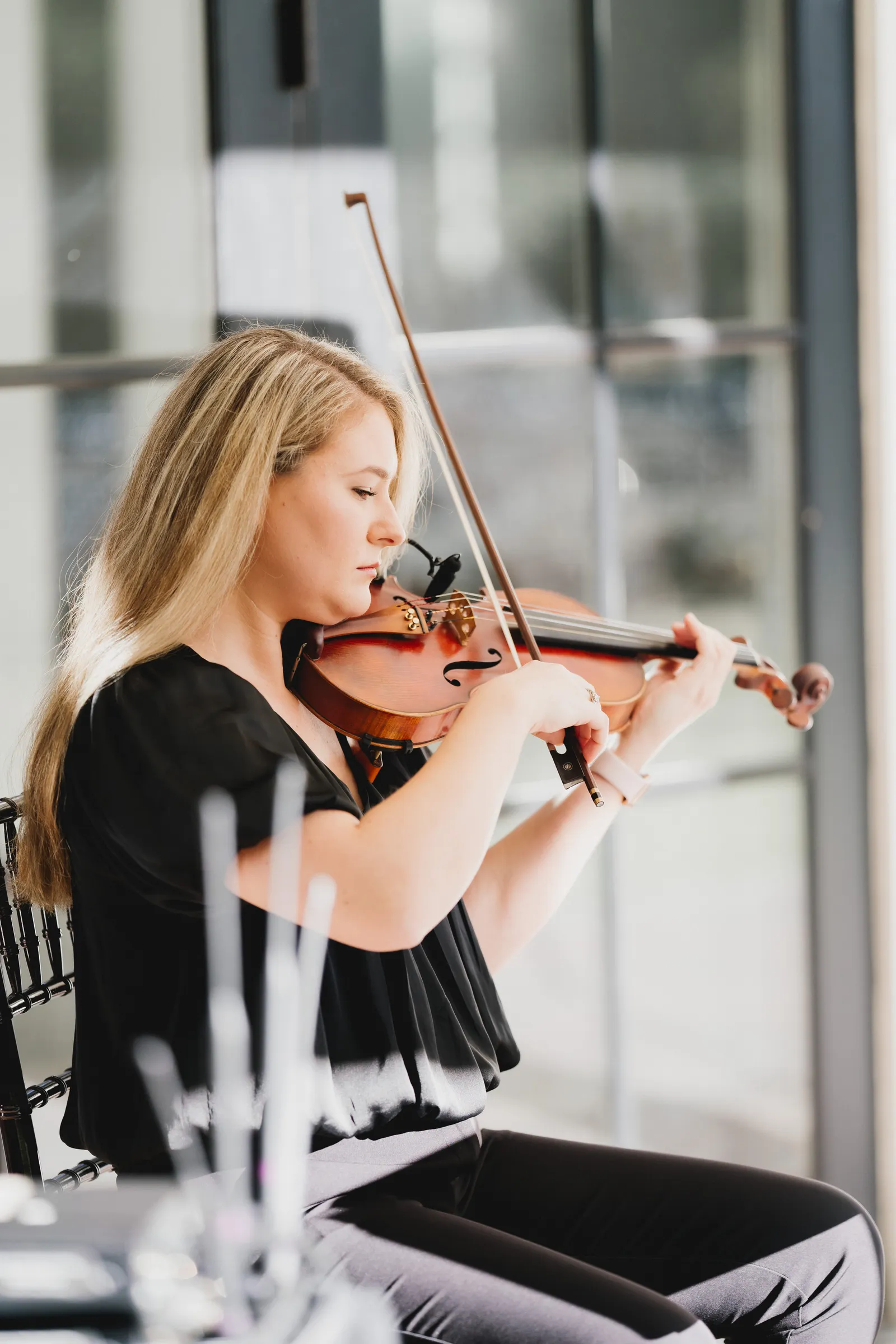 Solo violinist performing beside a modern glass building